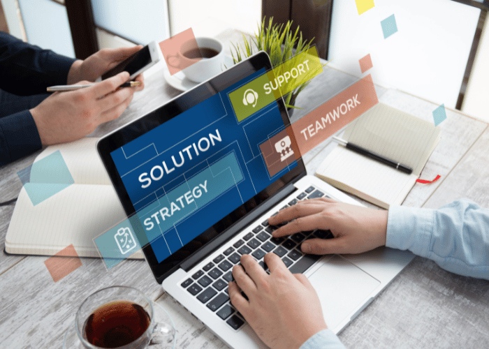 Man on laptop typing with the laptop screen that displays Solution Support Strategy Teamwork